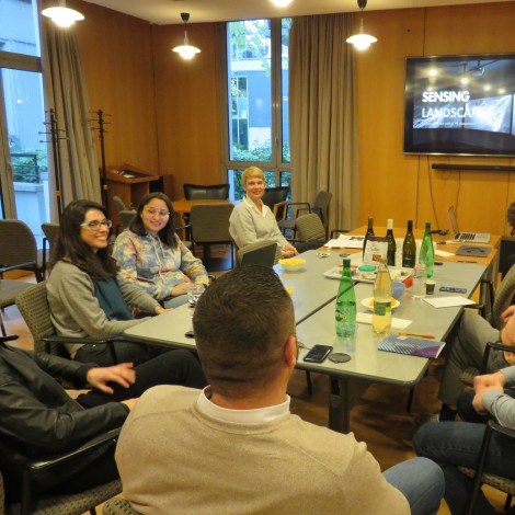 Eight people are gathered around a conference room table for a discussion