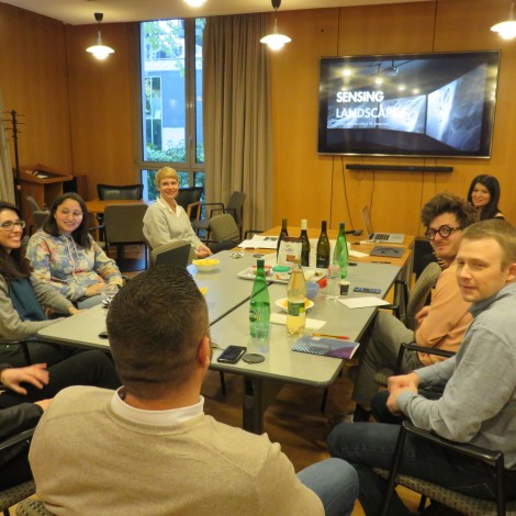 Eight people are gathered around a conference room table for a discussion